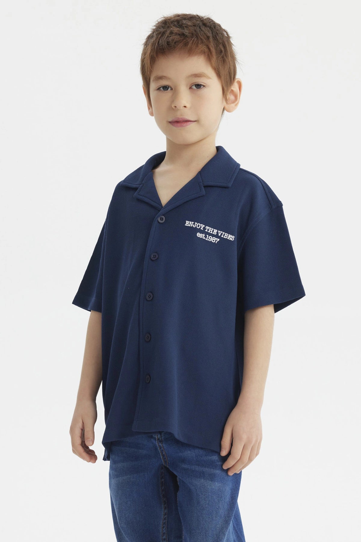 Camisa azul para niño con botones y texto blanco Enjoy the Vibes en el pecho diseño casual y moderno