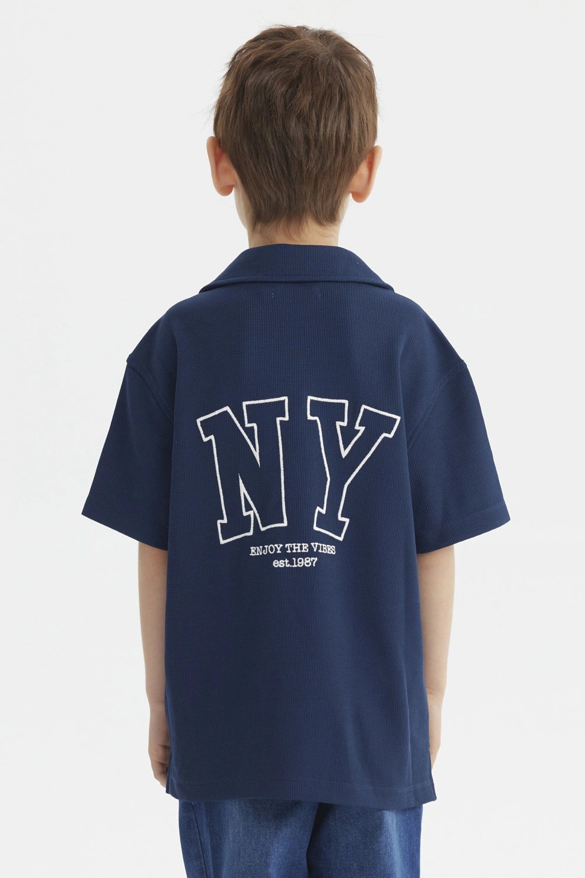 Camisa azul para niño con botones y texto blanco Enjoy the Vibes en el pecho diseño casual y moderno