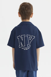 Camisa azul para niño con botones y texto blanco Enjoy the Vibes en el pecho diseño casual y moderno