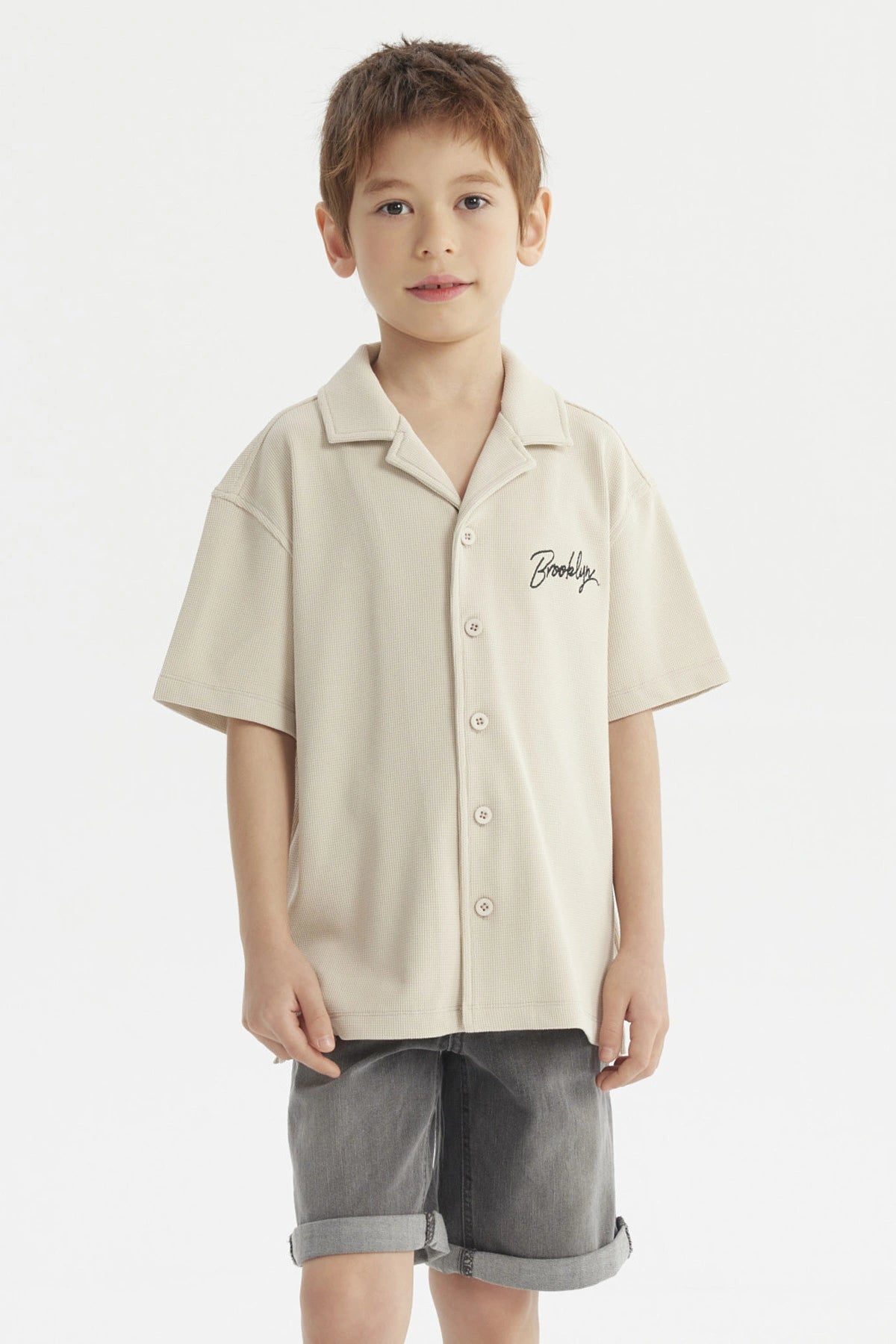 Camisa niño color crudo con cuello abierto y texto Brooklyn en el pecho estilo casual sin estampa adicional