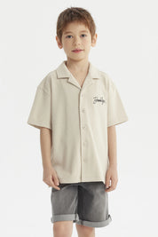 Camisa niño color crudo con cuello abierto y texto Brooklyn en el pecho estilo casual sin estampa adicional