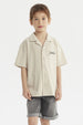 Camisa niño color crudo con cuello abierto y texto Brooklyn en el pecho estilo casual sin estampa adicional