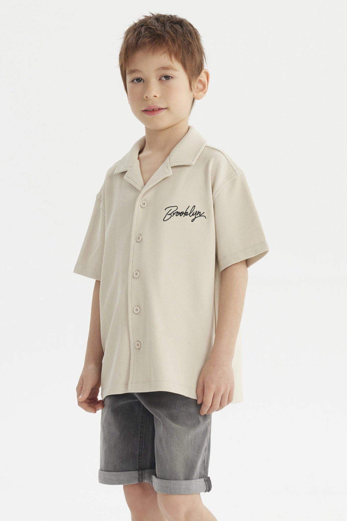 Camisa niño color crudo con cuello abierto y texto Brooklyn en el pecho estilo casual sin estampa adicional