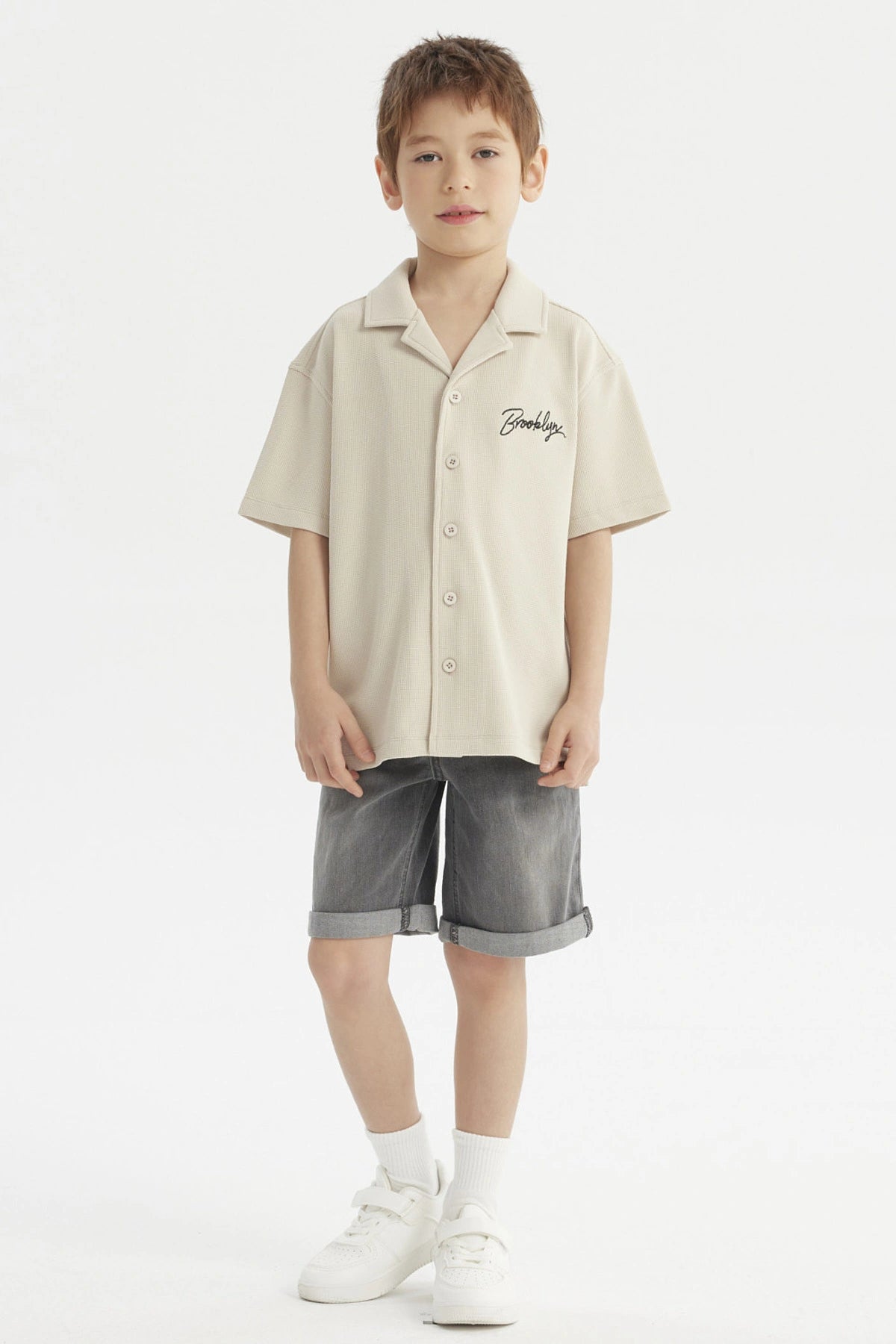 Camisa niño color crudo con cuello abierto y texto Brooklyn en el pecho estilo casual sin estampa adicional