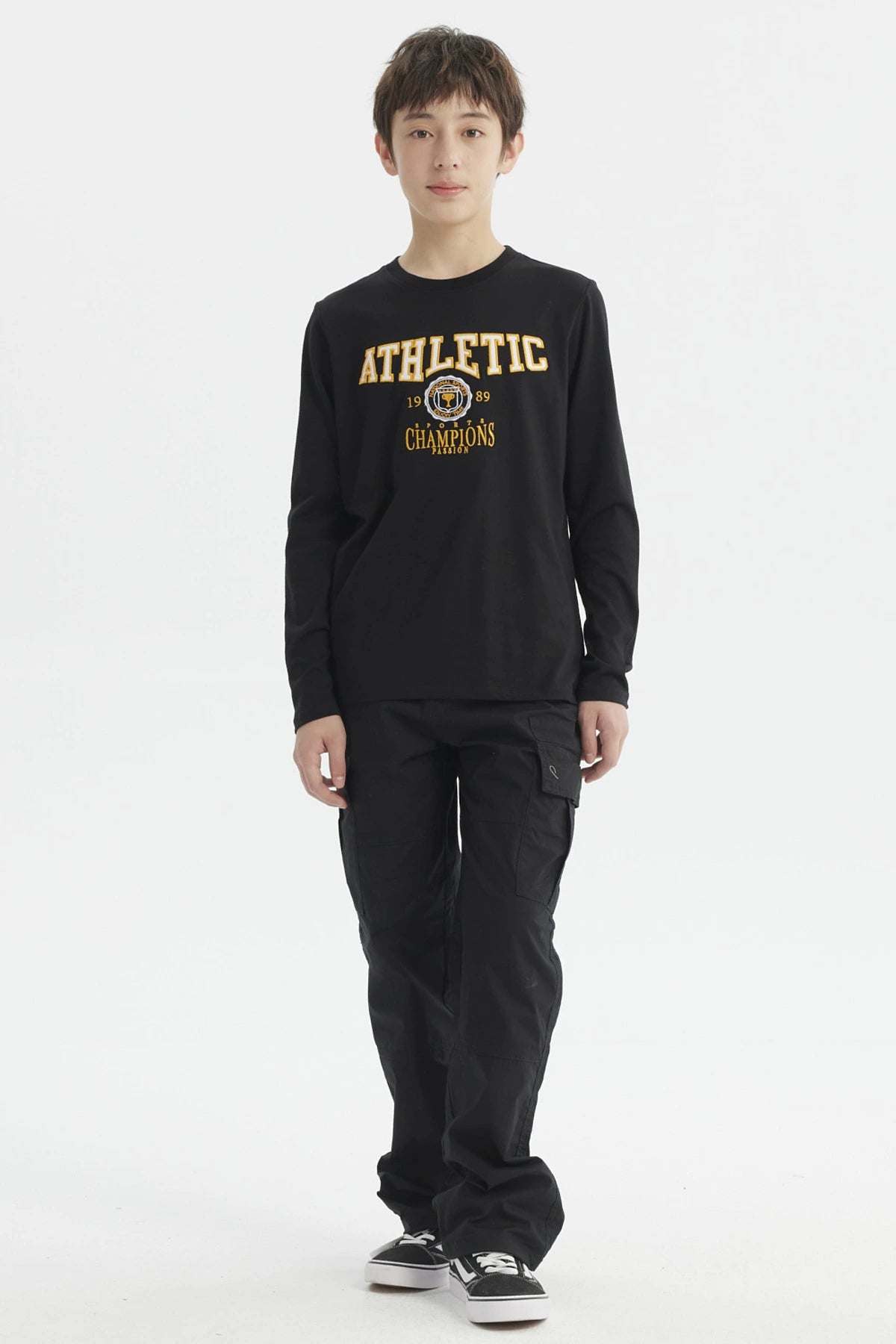Polera negra de niño con estampado bordado estilo college en el pecho que dice ATHLETIC y detalles en amarillo