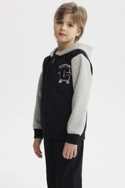 Chaqueta negra para niño con capucha y mangas grises diseño Champion C en el pecho estilo casual urbano
