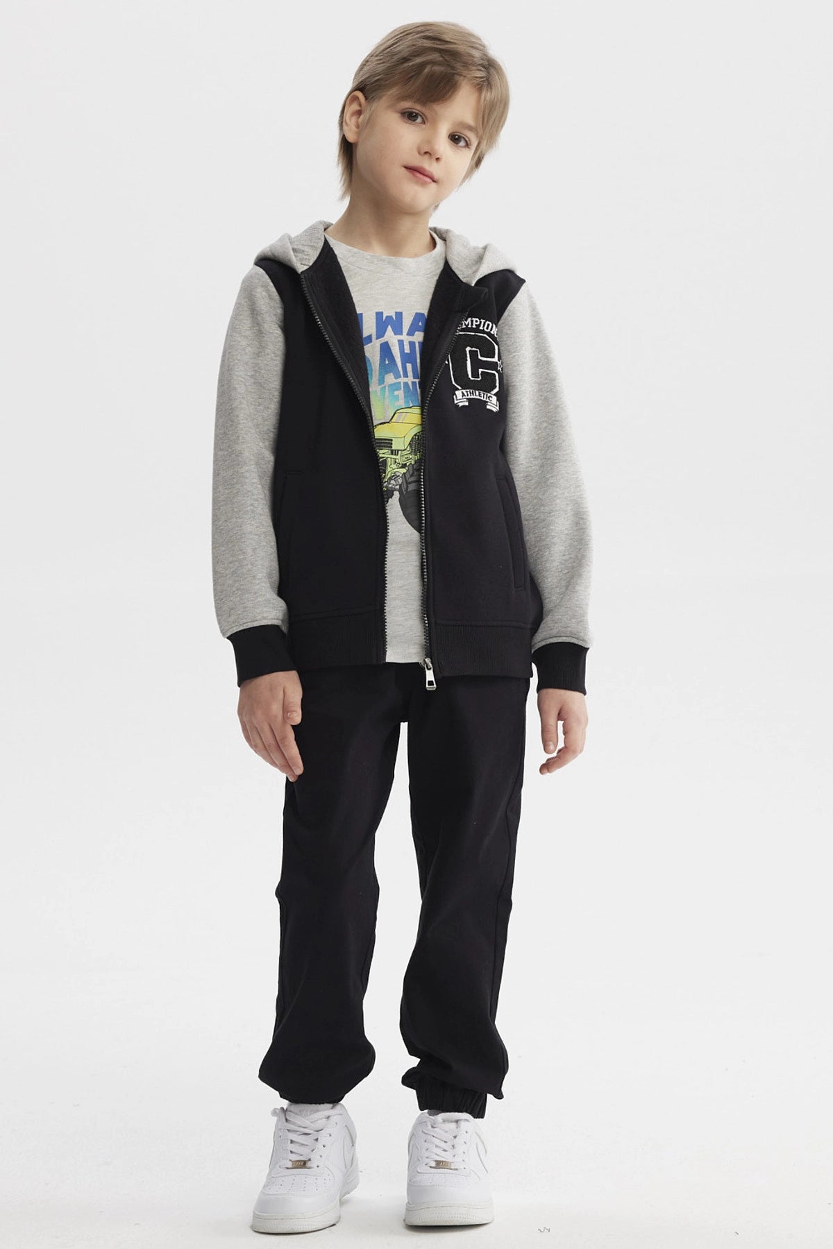 Chaqueta negra para niño con capucha y mangas grises diseño Champion C en el pecho estilo casual urbano