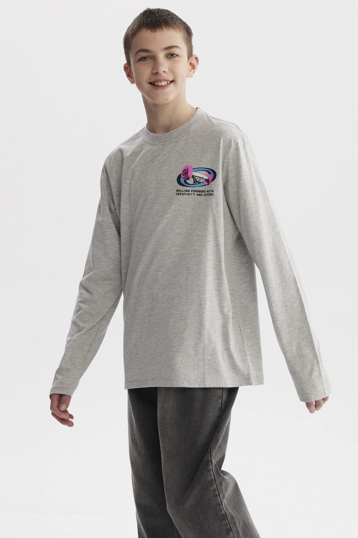 Polera niño slim gris melange con diseño gráfico pequeño en el pecho de rosa y texto Rolling Forward With Creativity and Nature