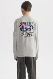 Polera niño slim gris melange con diseño gráfico pequeño en el pecho de rosa y texto Rolling Forward With Creativity and Nature