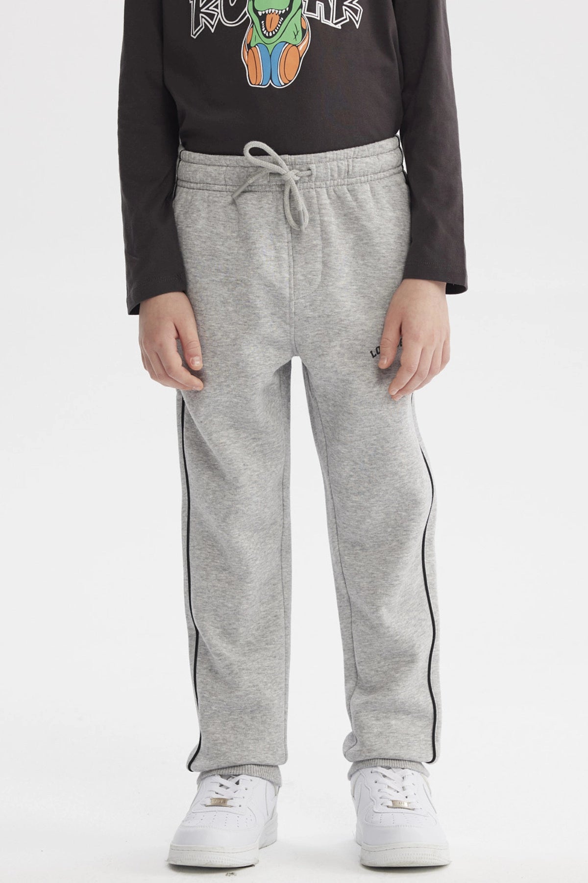 Pantalón buzo pitillo gris melange para niño con cintura ajustable y línea negra en el costado prenda lisa