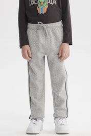 Pantalón buzo pitillo gris melange para niño con cintura ajustable y línea negra en el costado prenda lisa