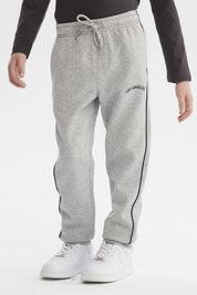 Pantalón buzo pitillo gris melange para niño con cintura ajustable y línea negra en el costado prenda lisa