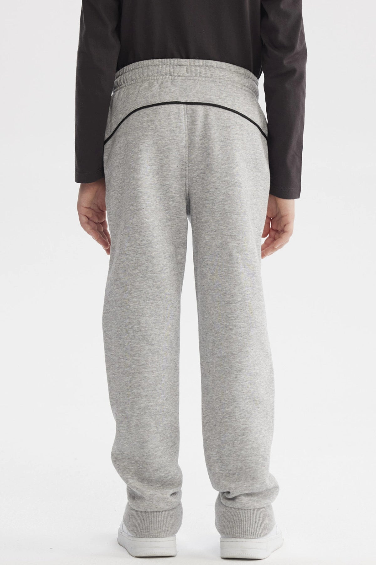 Pantalón buzo pitillo gris melange para niño con cintura ajustable y línea negra en el costado prenda lisa