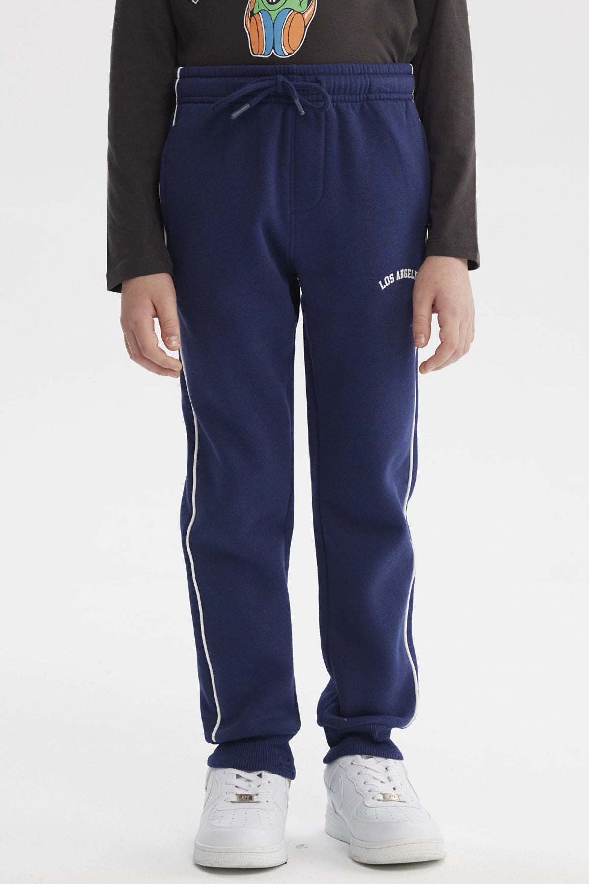 Pantalón buzo niño azul oscuro con líneas blancas laterales y texto Los Angeles en la cadera sin estampa visible