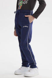 Pantalón buzo niño azul oscuro con líneas blancas laterales y texto Los Angeles en la cadera sin estampa visible