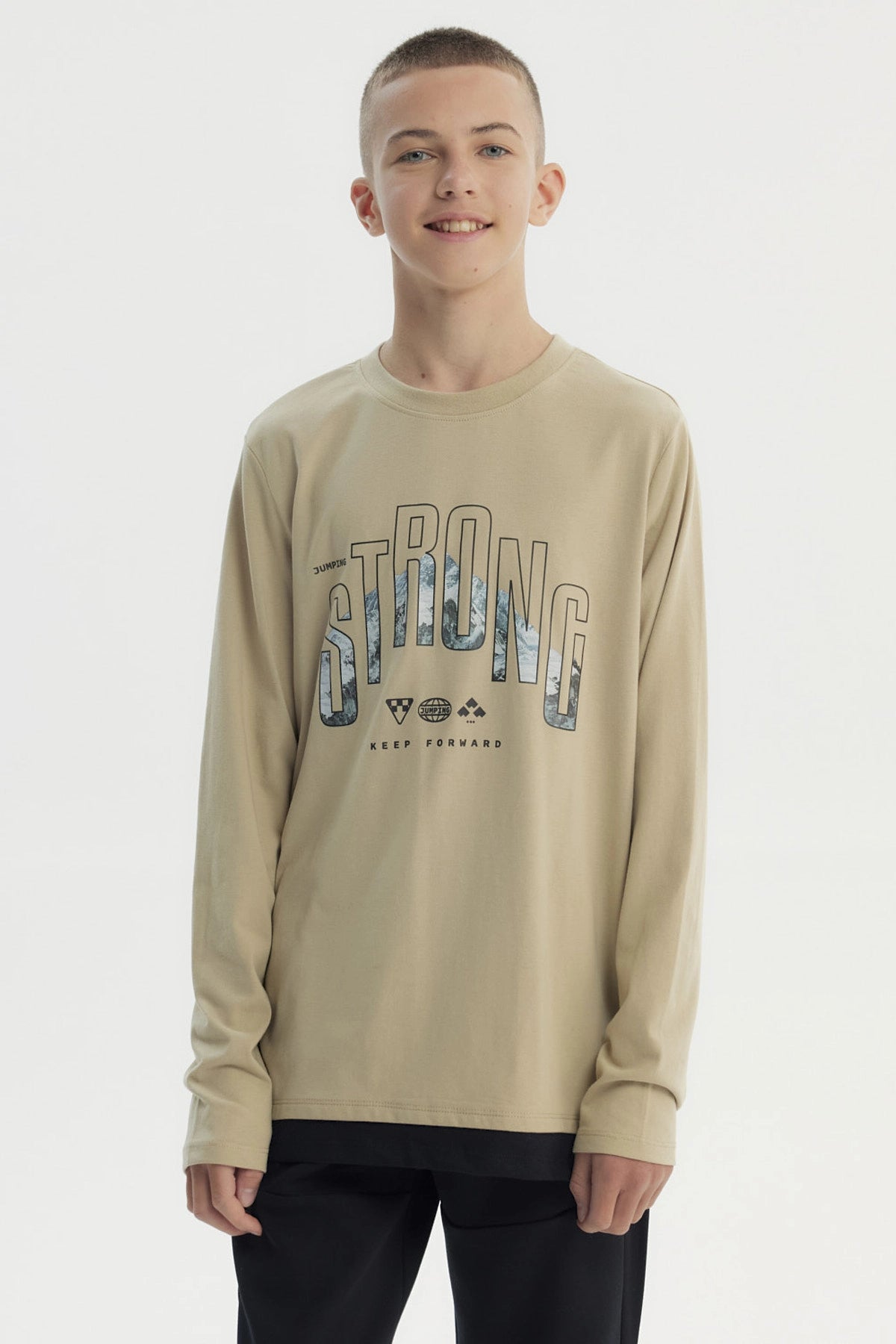 Polera slim kaki para niño con diseño frontal de texto Strong y paisaje montañoso estilo gráfico centrado