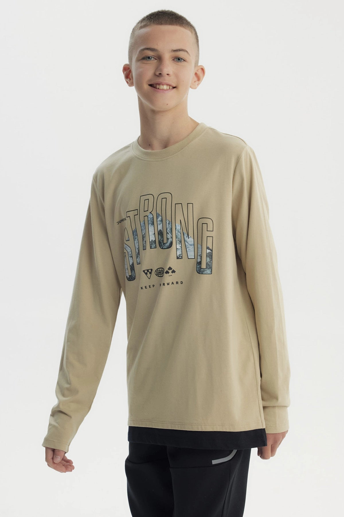 Polera slim kaki para niño con diseño frontal de texto Strong y paisaje montañoso estilo gráfico centrado