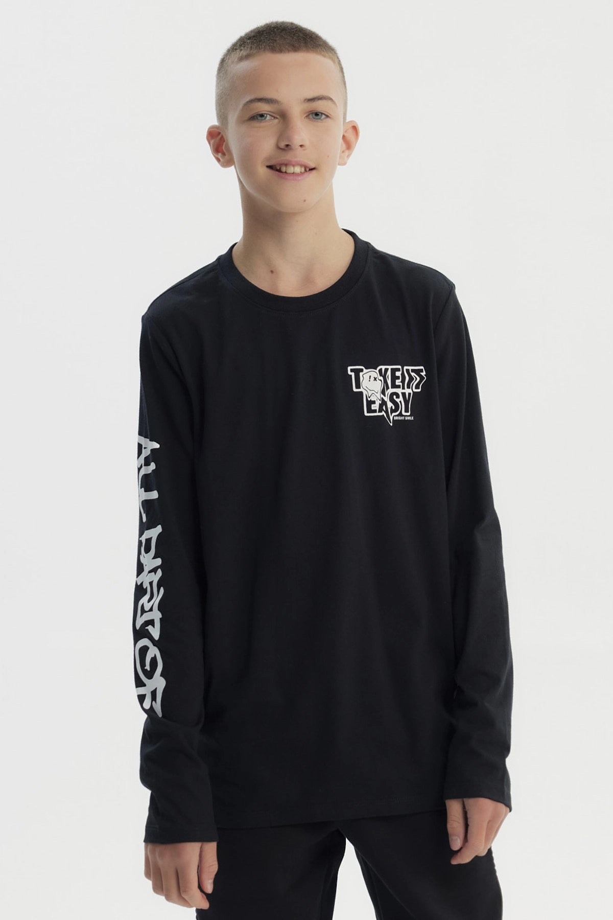 Polera negra de niño con diseño "Take it Easy" en el pecho y texto en la manga izquierda estilo urbano