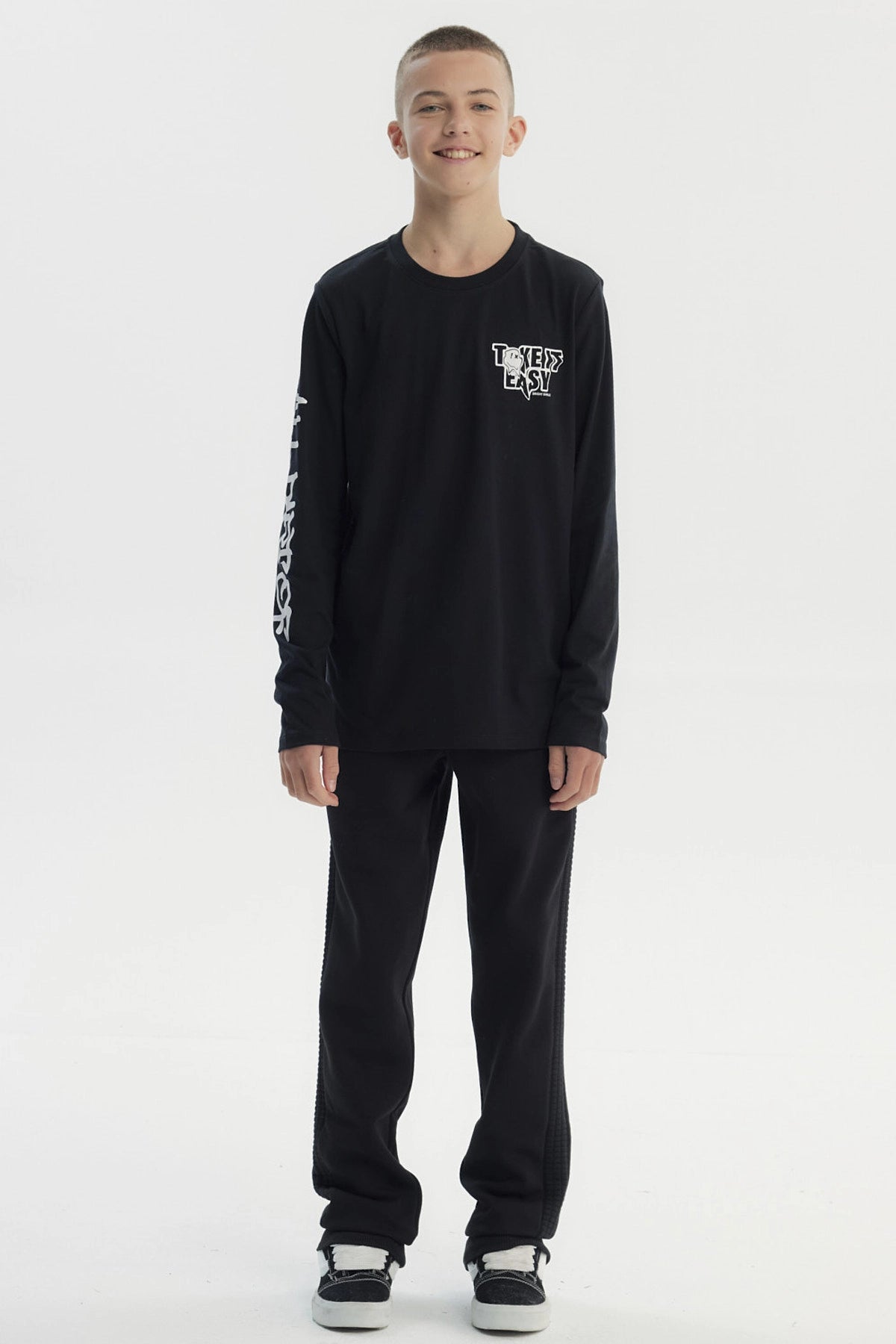 Polera negra de niño con diseño "Take it Easy" en el pecho y texto en la manga izquierda estilo urbano