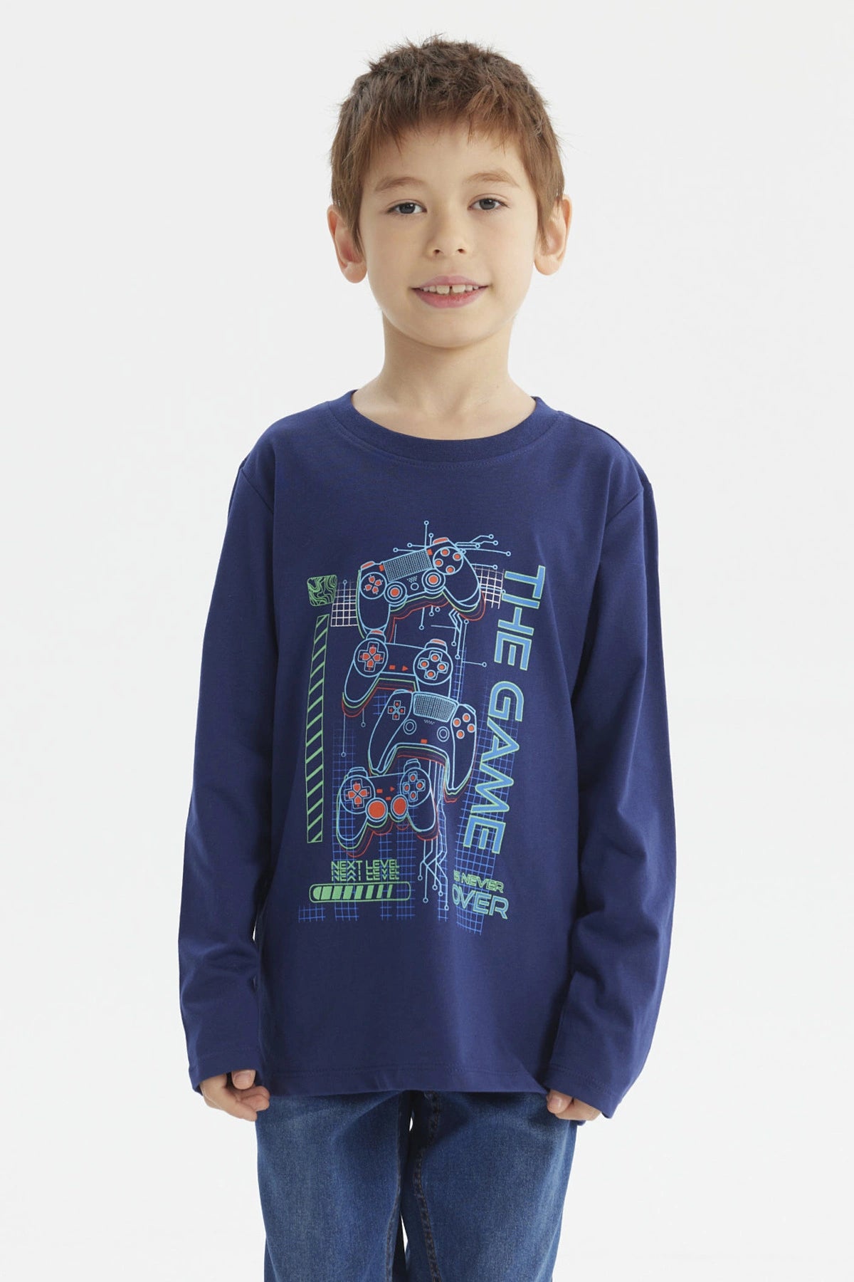 Polera de niño azul oscuro con estampado central de controles de videojuegos y texto The Game en estilo moderno