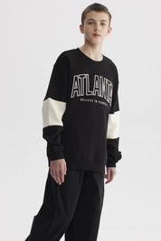 Polerón negro para niño con franjas blancas y texto ATLANTA en el pecho estilo casual gráfico moderno