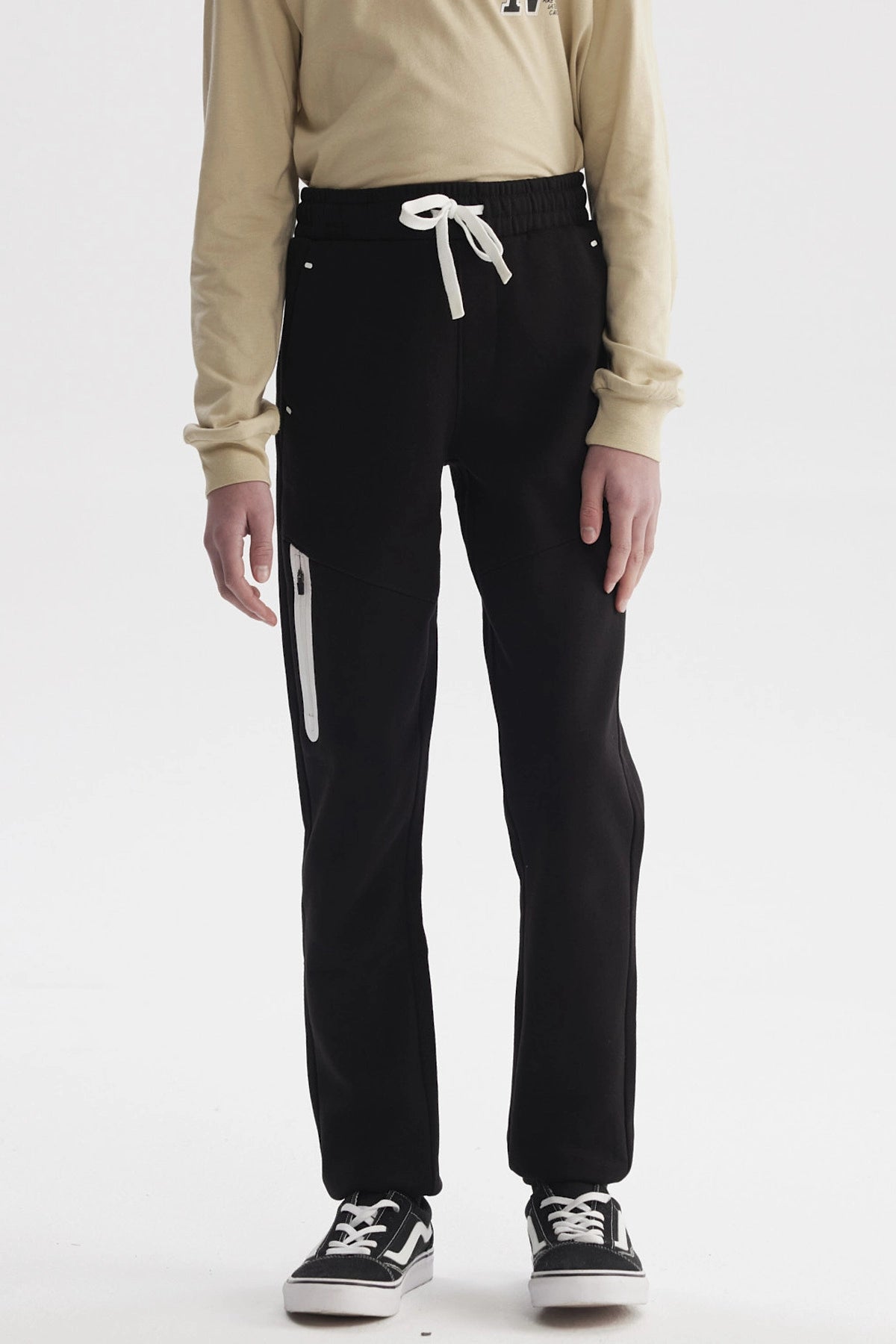 Pantalón buzo negro para niño con ajuste pitillo y bolsillo con cierre blanco lateral