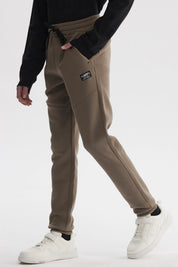 Pantalón buzo niño pitillo café claro liso con ajuste de cordón en la cintura y bolsillos laterales pequeños