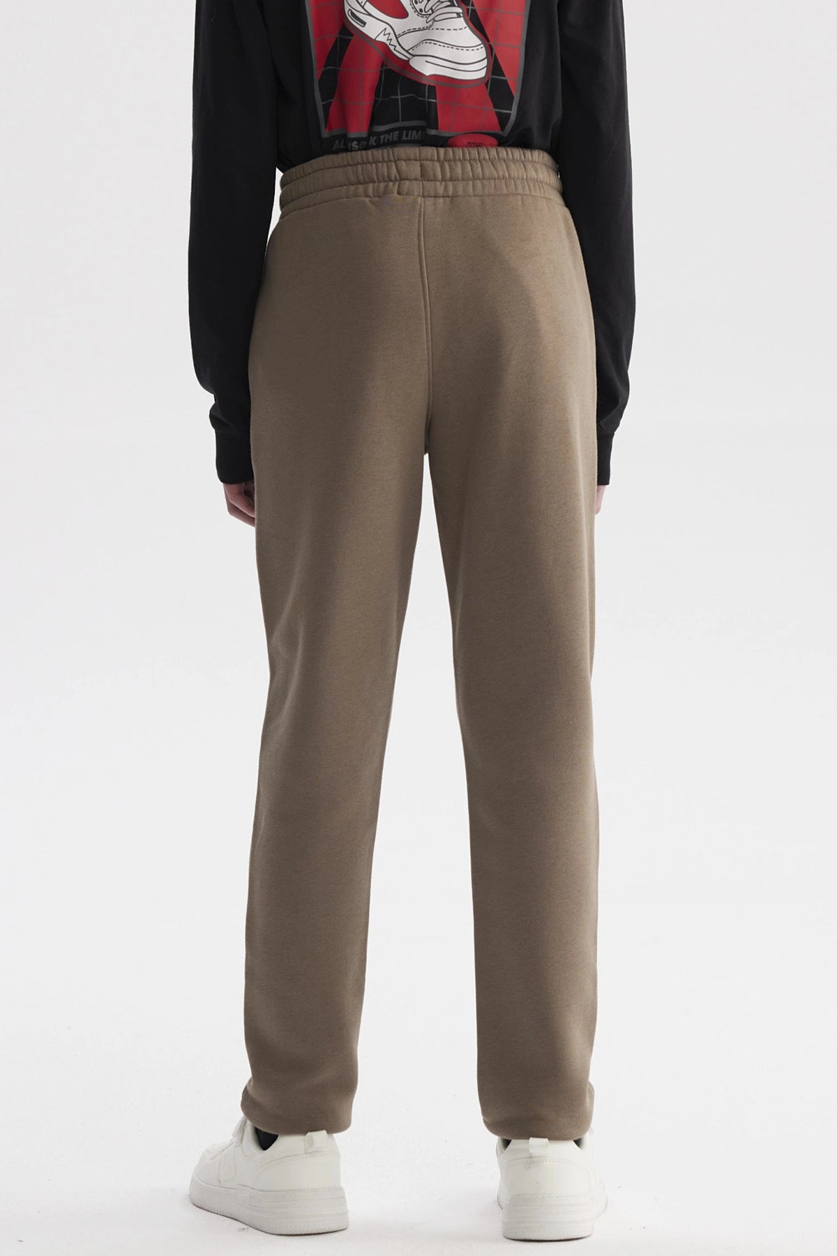 Pantalón buzo niño pitillo café claro liso con ajuste de cordón en la cintura y bolsillos laterales pequeños