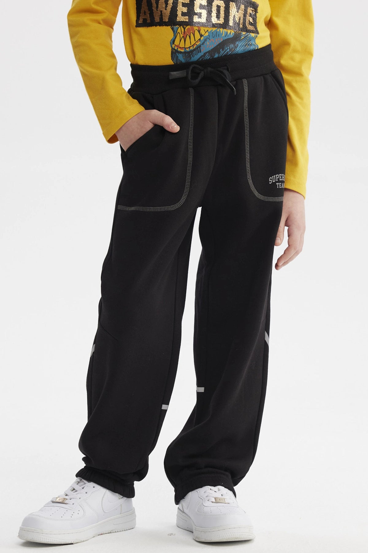 Pantalón buzo negro para niño con bolsillos y ajuste en cintura estampa blanca pequeña lateral "SUPER TEAM"
