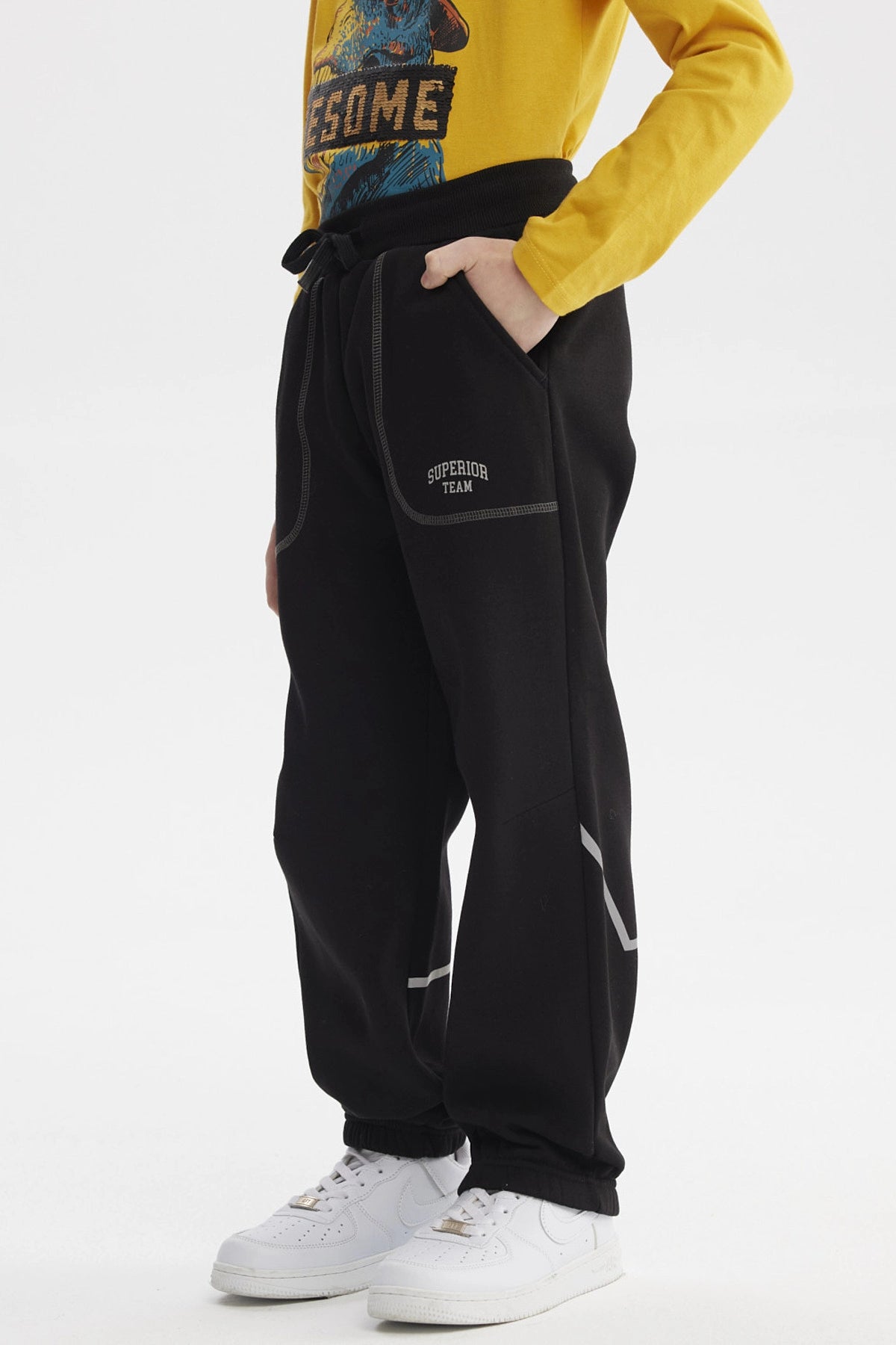Pantalón buzo negro para niño con bolsillos y ajuste en cintura estampa blanca pequeña lateral "SUPER TEAM"