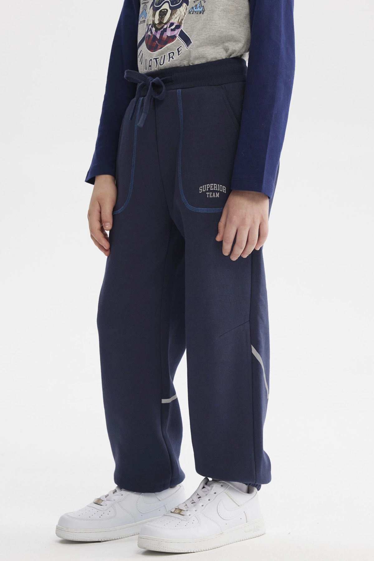 Pantalón buzo azul niño con ajuste en la cintura bolsillos delanteros y detalle de texto pequeño en el lateral izquierdo
