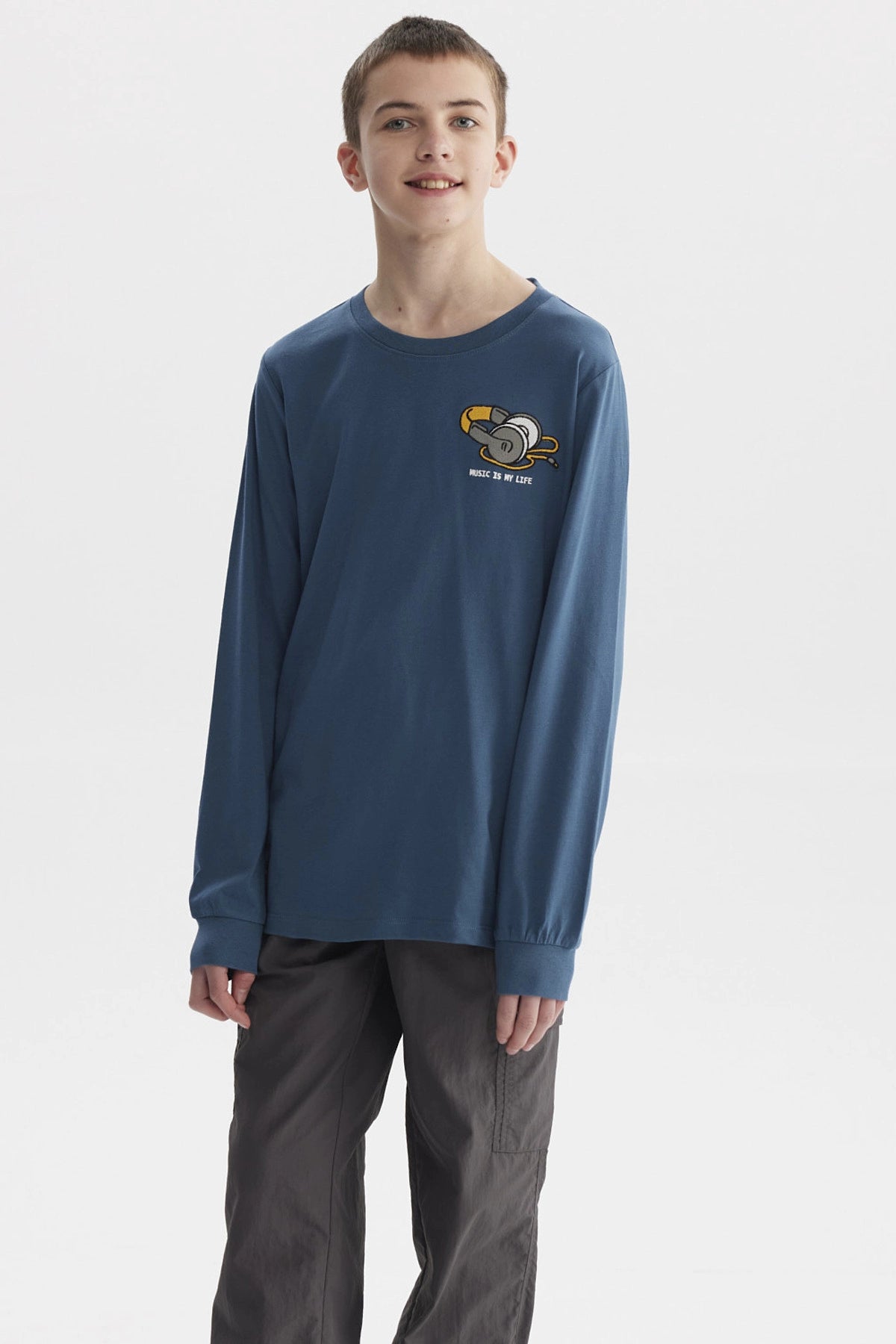 Polera azul petróleo de niño con estampado de audífonos y texto Music is my life en el pecho estilo gráfico pequeño
