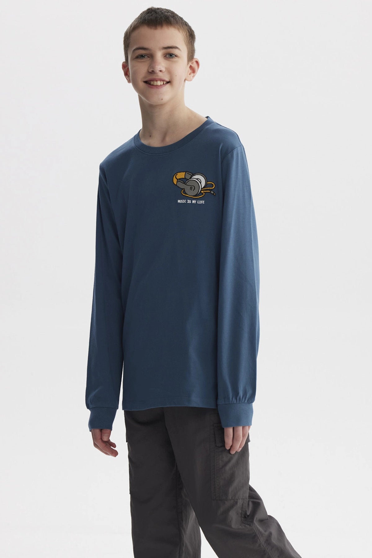 Polera azul petróleo de niño con estampado de audífonos y texto Music is my life en el pecho estilo gráfico pequeño