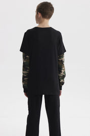 Polera negra de niño con mangas dobles camufladas y estampado de skater pequeño en el pecho estilo gráfico urbano