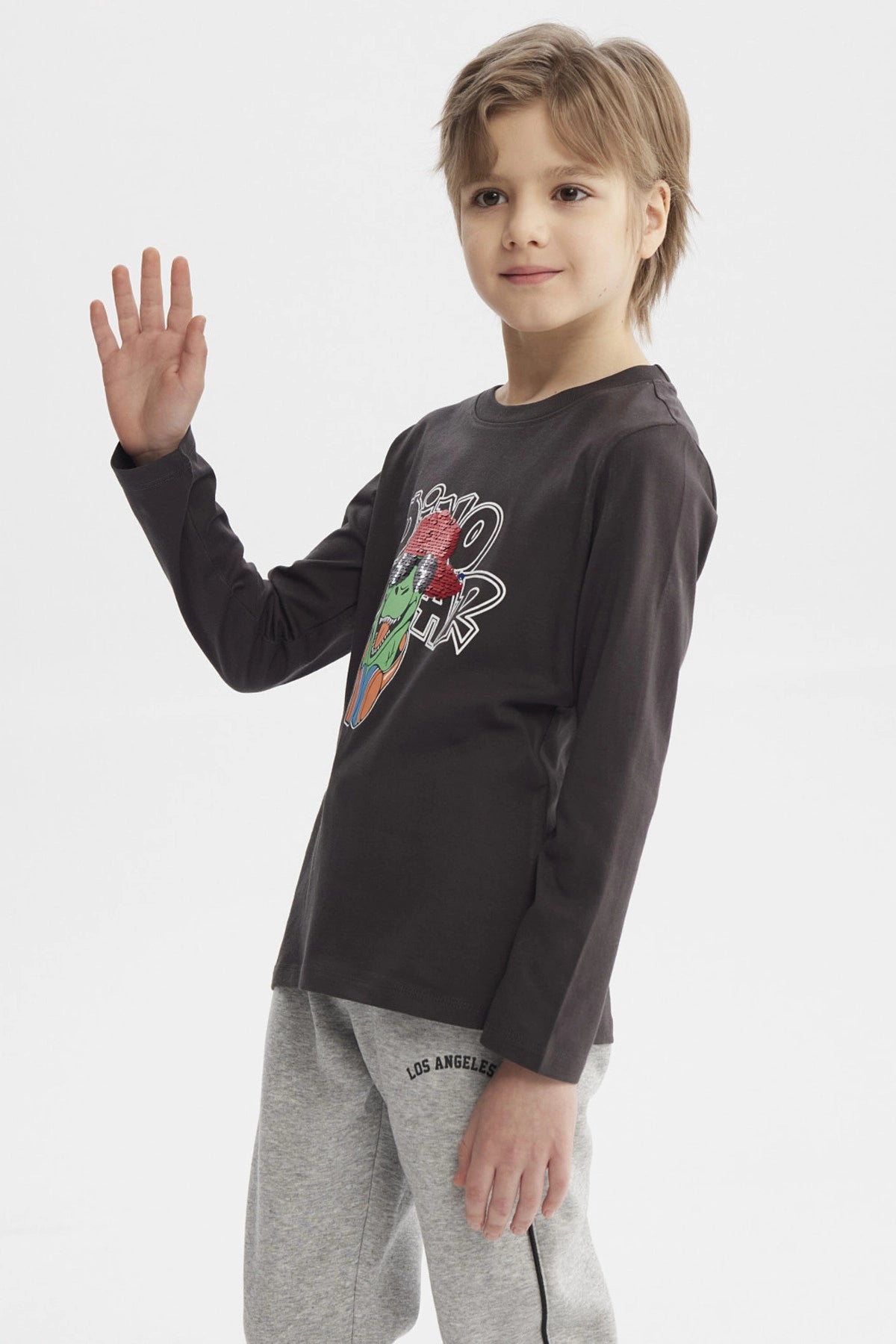 Polera de niño marengo con estampado de dinosaurio rockero con audífonos y gorra roja en el centro estilo dibujo animado