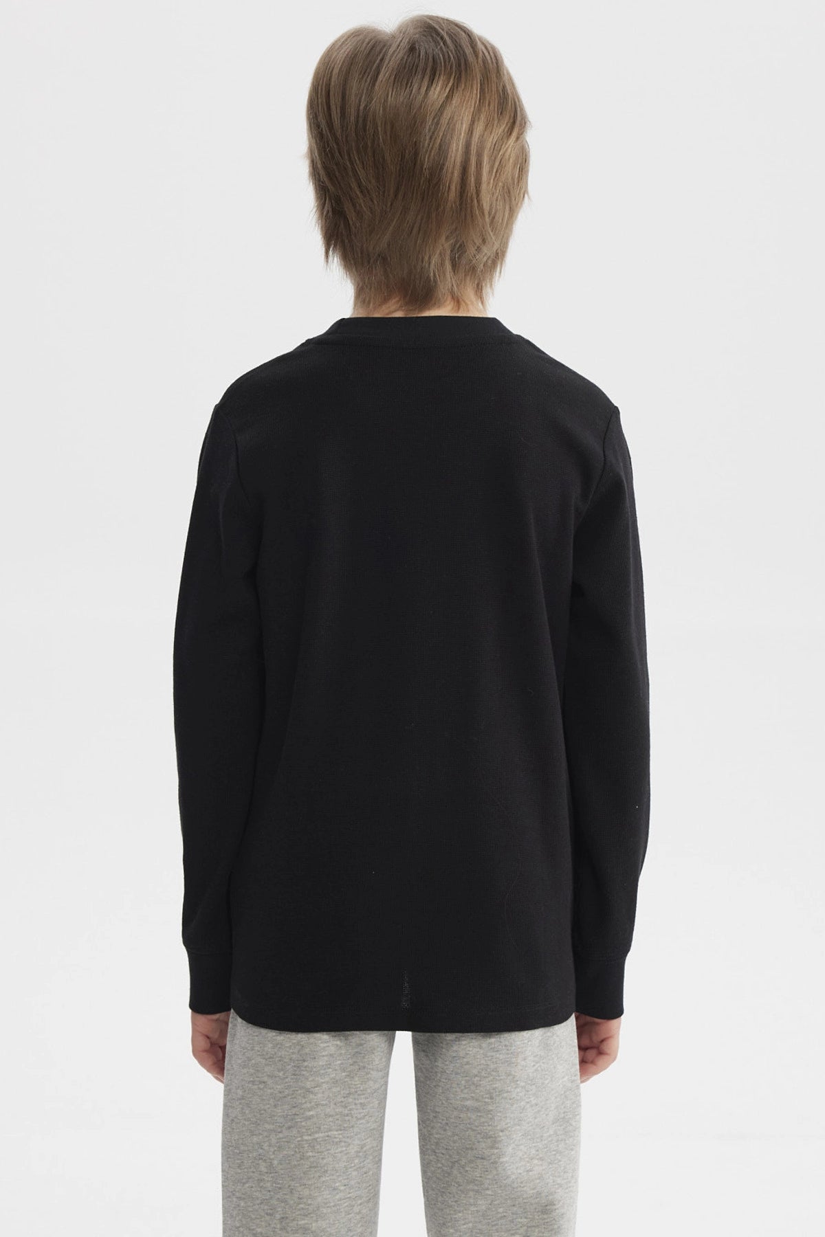 Polera niño negra con estampa blanca de dinosaurio y texto Dinos Epic Team en el pecho estilo universitario casual