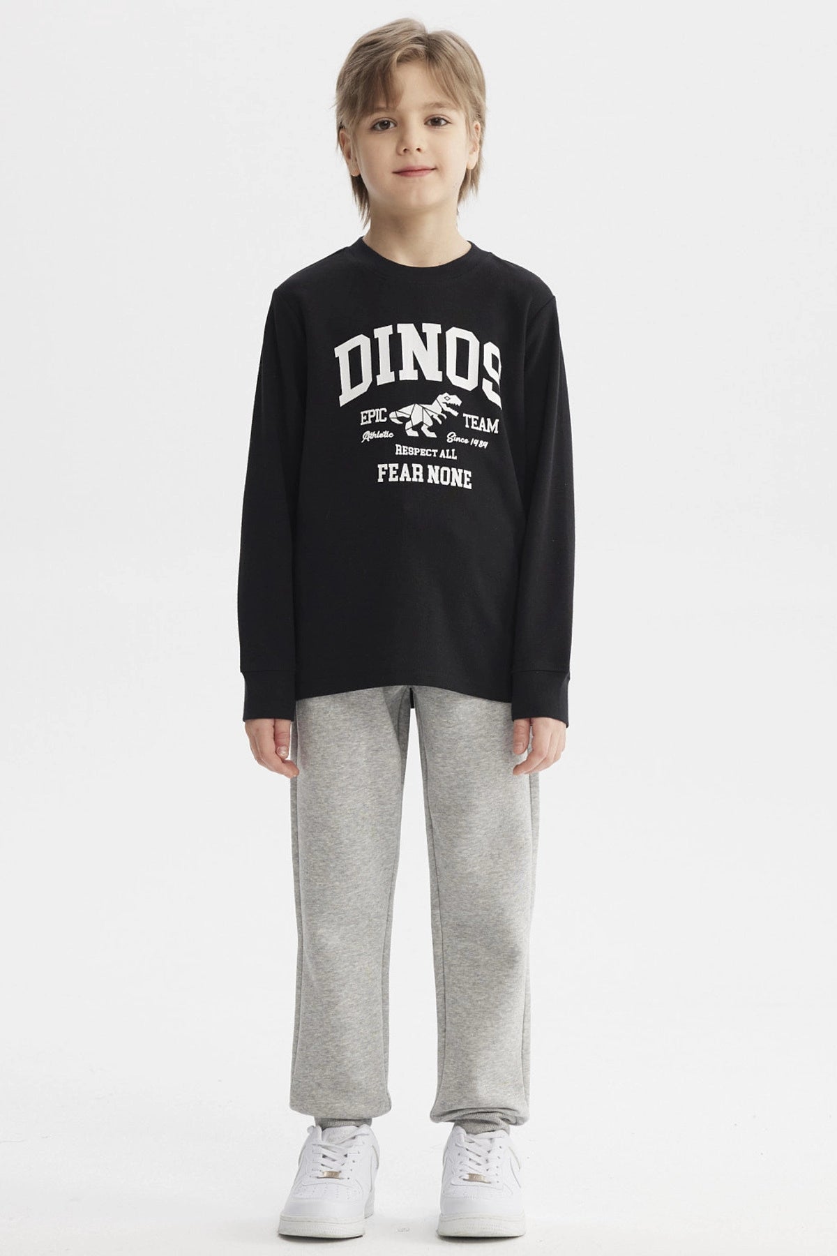 Polera niño negra con estampa blanca de dinosaurio y texto Dinos Epic Team en el pecho estilo universitario casual