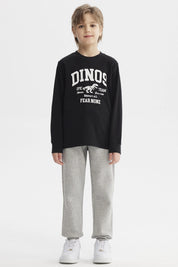 Polera niño negra con estampa blanca de dinosaurio y texto Dinos Epic Team en el pecho estilo universitario casual