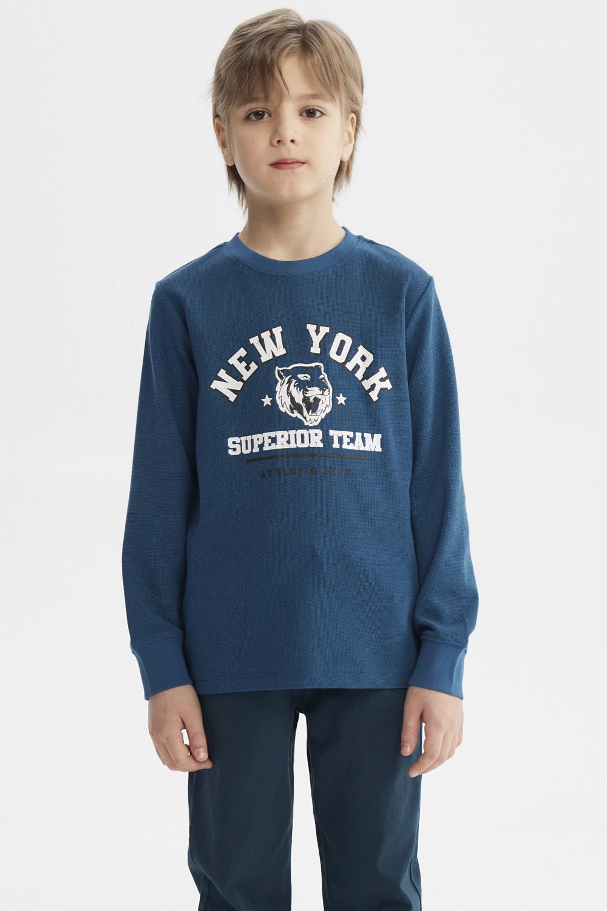 Polera niño azul petróleo con puños y estampa central de tigre y texto New York Superior Team estilo deportivo
