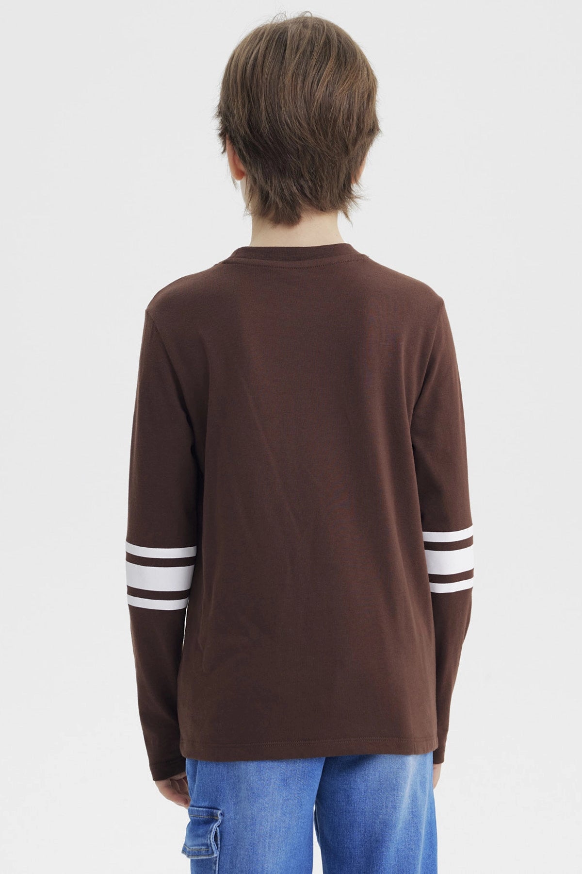 Polera slim café para niño con texto Shibuya Tokyo en el pecho y detalles gráficos urbanos manga larga con rayas blancas