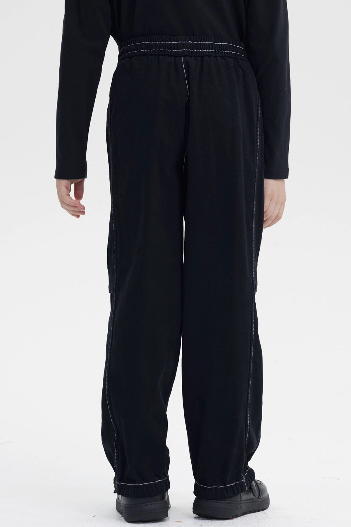 Pantalón niño pitillo negro con costuras visibles y cintura elástica la prenda es lisa