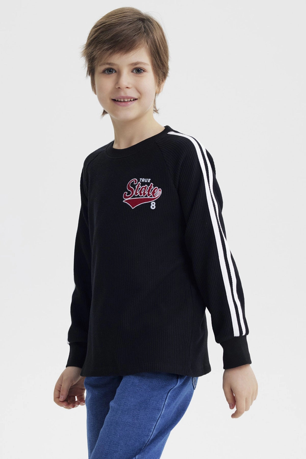 Polera niño negra con textura bicolor con texto True State 8 en el pecho diseño casual con líneas blancas en las mangas