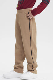Pantalón buzo pitillo kaki para niño con líneas negras laterales sin estampa visible cómodo y moderno