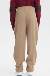 Pantalón buzo pitillo kaki para niño con líneas negras laterales sin estampa visible cómodo y moderno