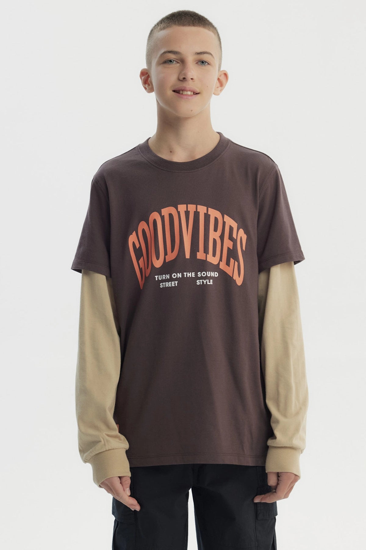 Polera slim café para niño con texto Good Vibes en el frente en estilo gráfico moderno sobre fondo liso