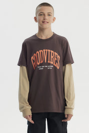 Polera slim café para niño con texto Good Vibes en el frente en estilo gráfico moderno sobre fondo liso