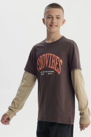 Polera slim café para niño con texto Good Vibes en el frente en estilo gráfico moderno sobre fondo liso