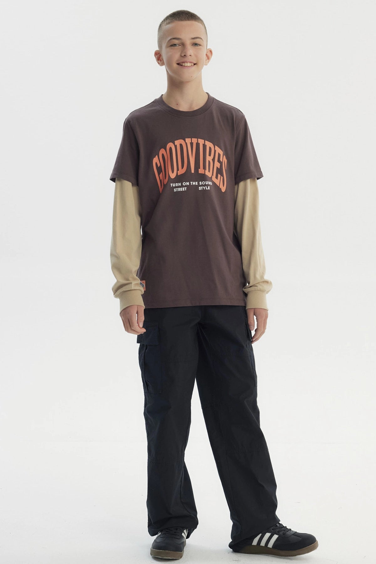 Polera slim café para niño con texto Good Vibes en el frente en estilo gráfico moderno sobre fondo liso