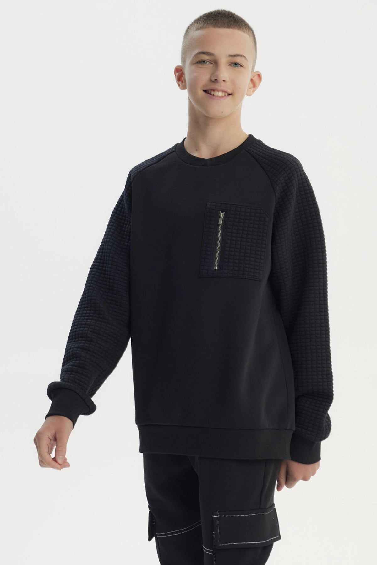 Polerón niño slim negro con textura en mangas y bolsillo frontal con cierre sin estampa visible
