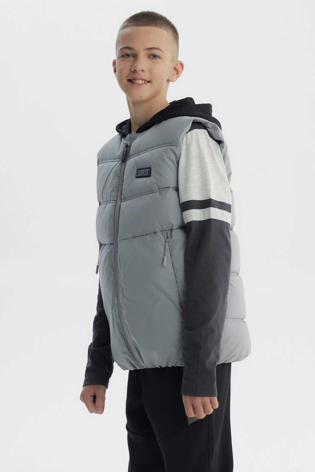 Parka sin mangas gris para niño con cremallera central y logo pequeño en el pecho estilo casual y moderno lisa